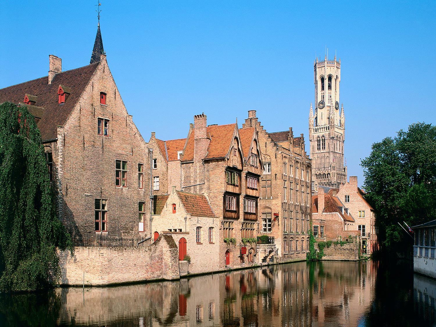 Pittoresk uitzicht op historische gebouwen langs een kanaal in Brugge met een blauwe lucht op de achtergrond en verwijzing naar de Minimax waterontharder.