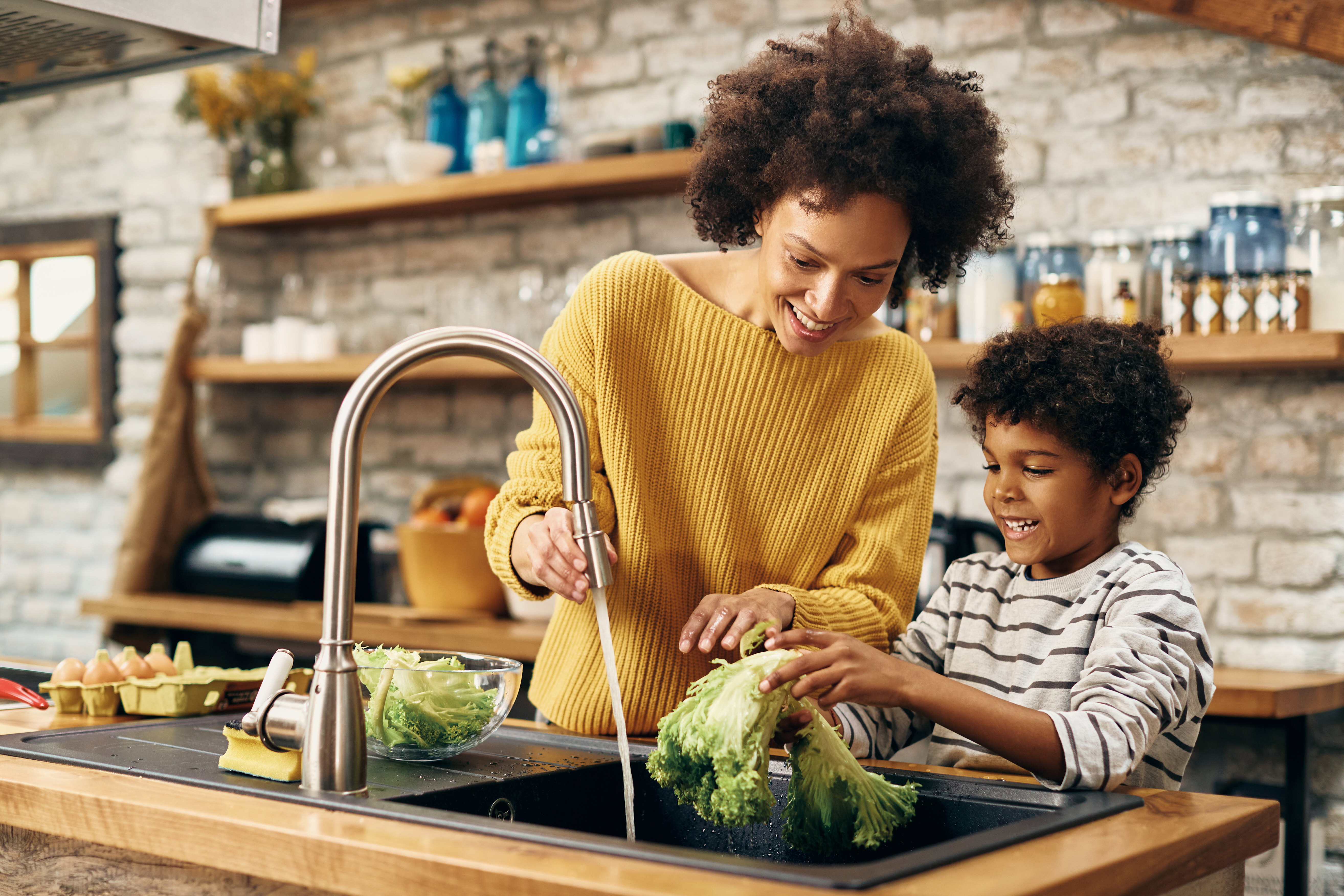 Femme et enfant lavant des légumes dans une cuisine avec de l’eau douce grâce à l’adoucisseur d’eau Minimax.