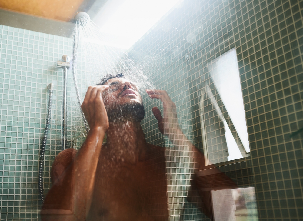 Homme profitant d’une douche avec de l’eau douce grâce à l’adoucisseur d’eau Minimax.