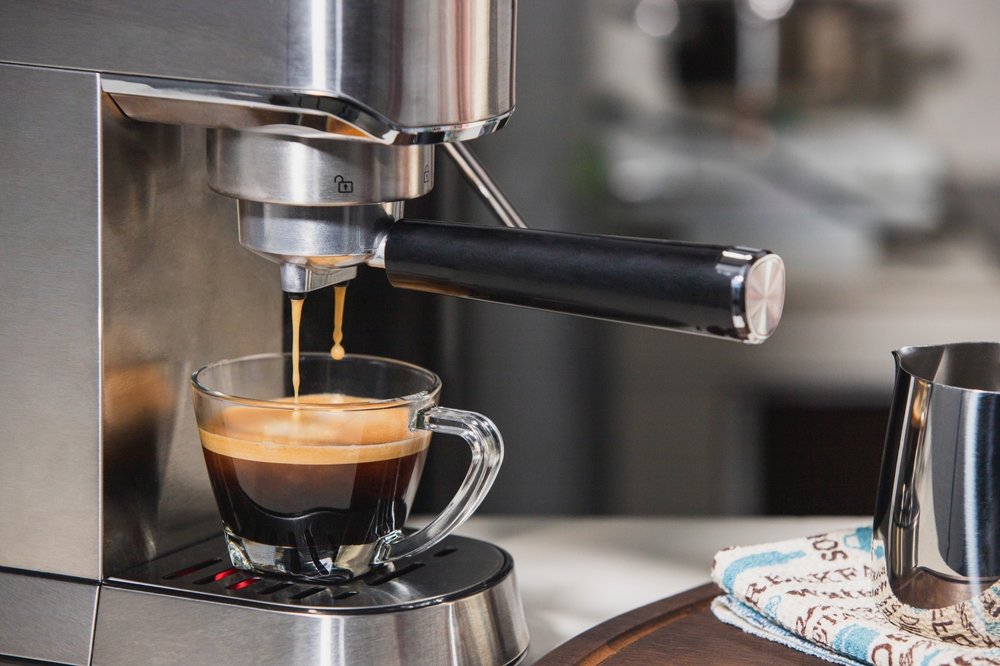 Machine à espresso versant un café fraîchement préparé dans un verre avec de l’eau douce de l’adoucisseur d’eau Minimax.