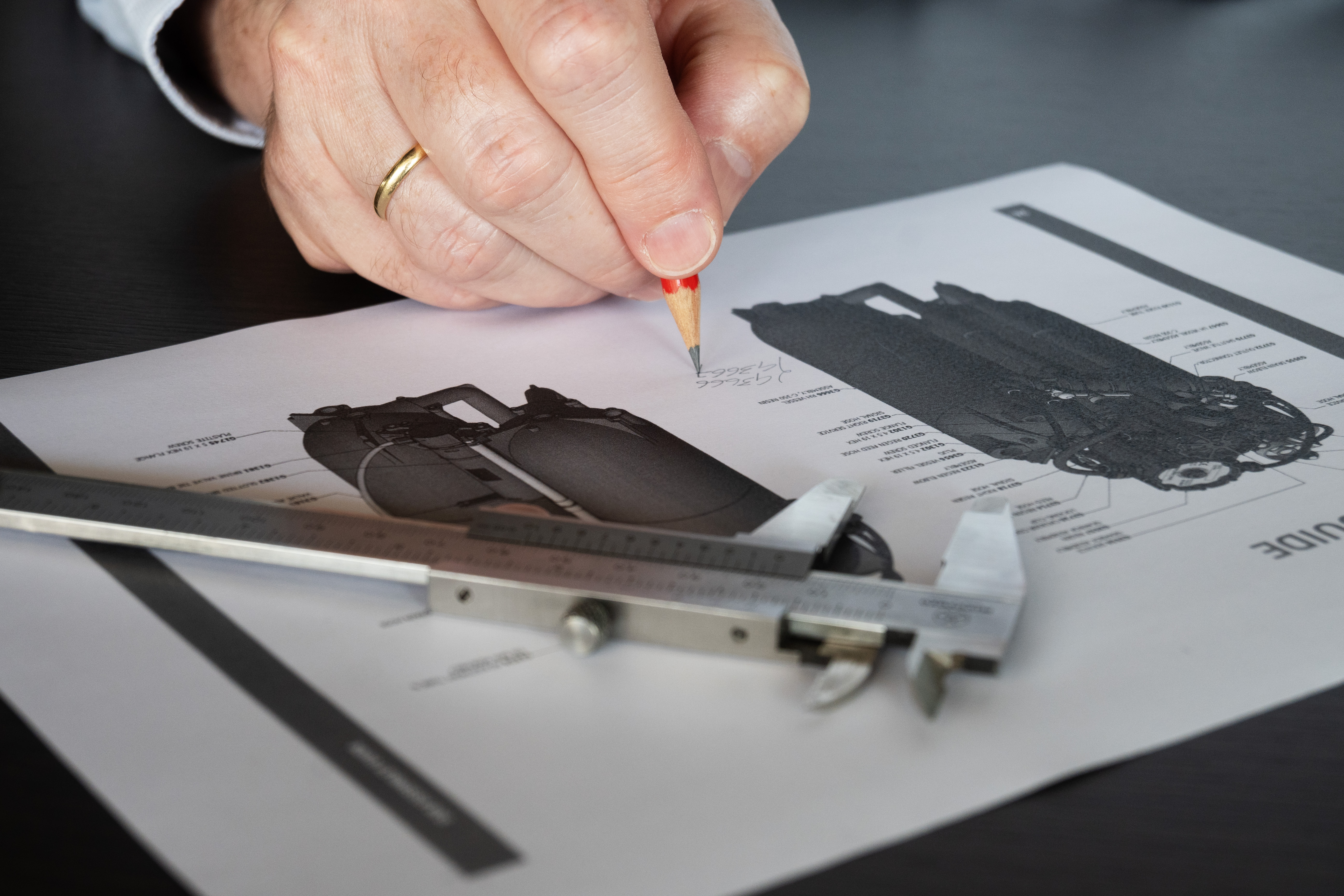 Main utilisant un pied à coulisse et un crayon pour prendre des mesures sur des plans techniques de l’adoucisseur d’eau Minimax.