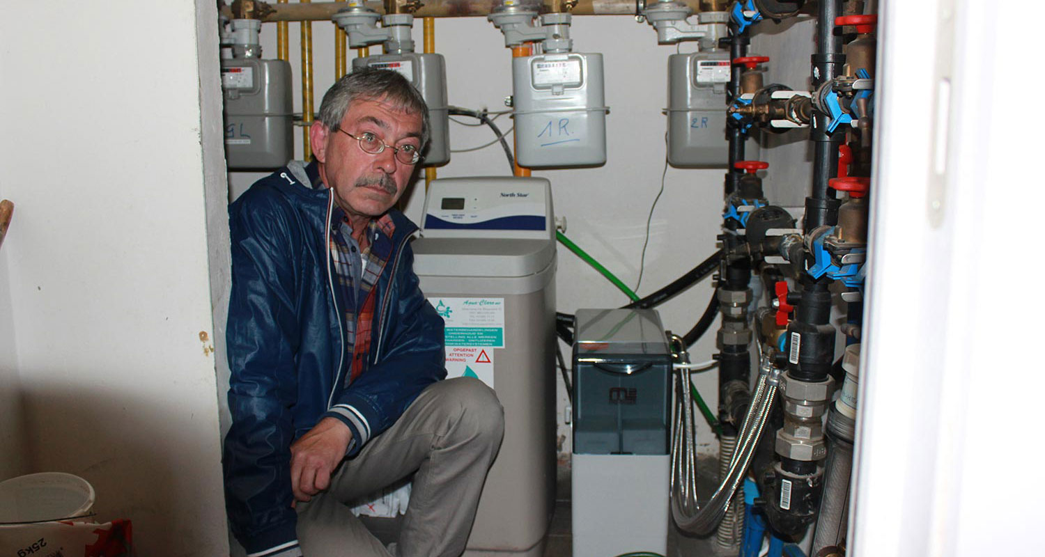 Man controleert een Minimax wateronthardersysteem in een technische ruimte.