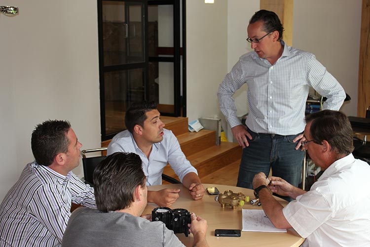 Groupe de personnes en réunion autour d’une table dans l’ancien bureau de l’adoucisseur d’eau Minimax avec Luc Chantraine, le créateur.